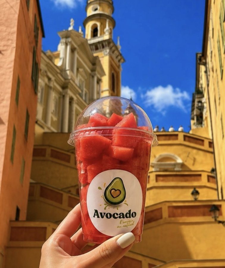 Un gobelet de fruits frais Avocado tenu devant la basilique Saint-Michel, dans la vieille ville de Menton